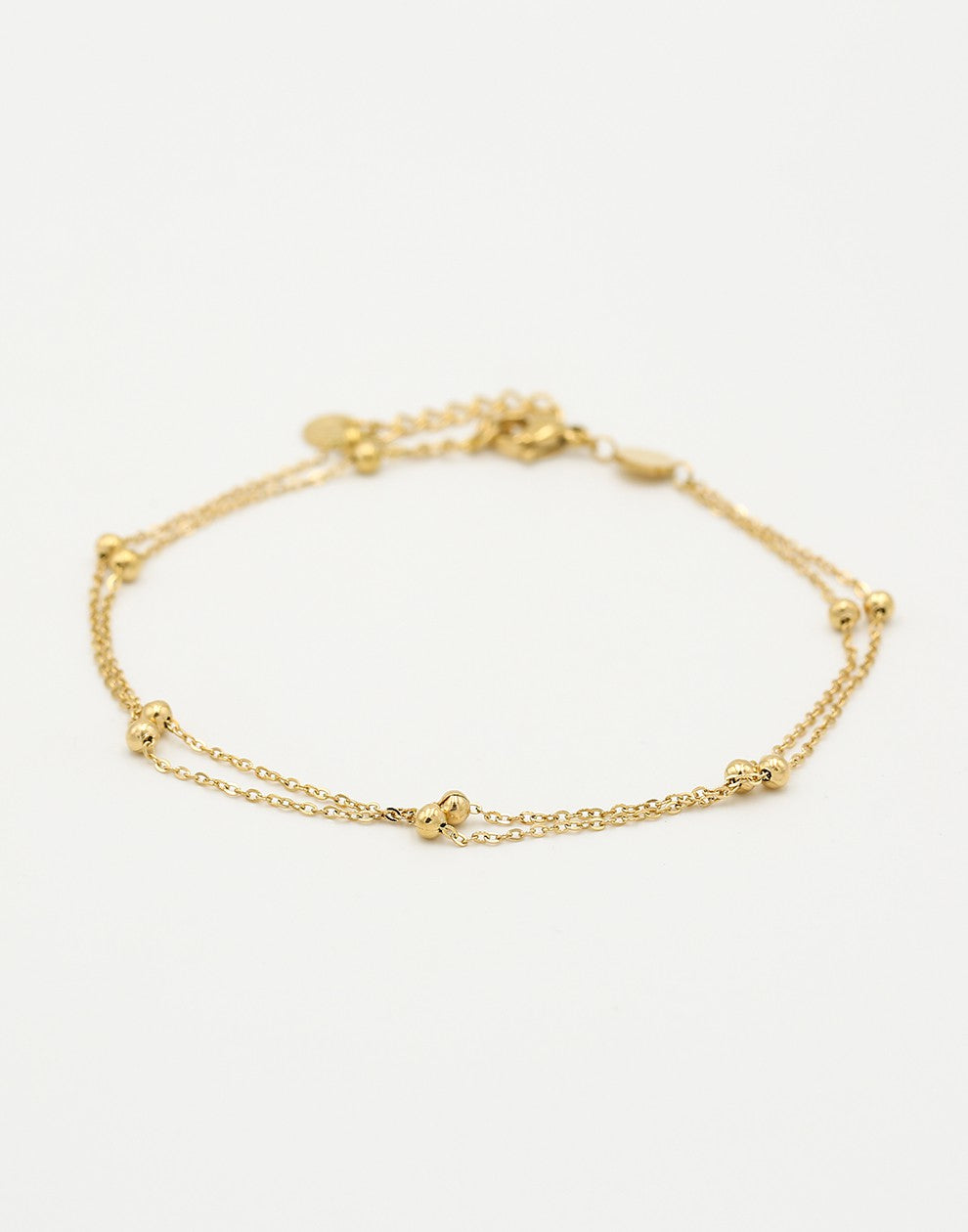 Ankle bracelet with double gold-colored beads and a chain