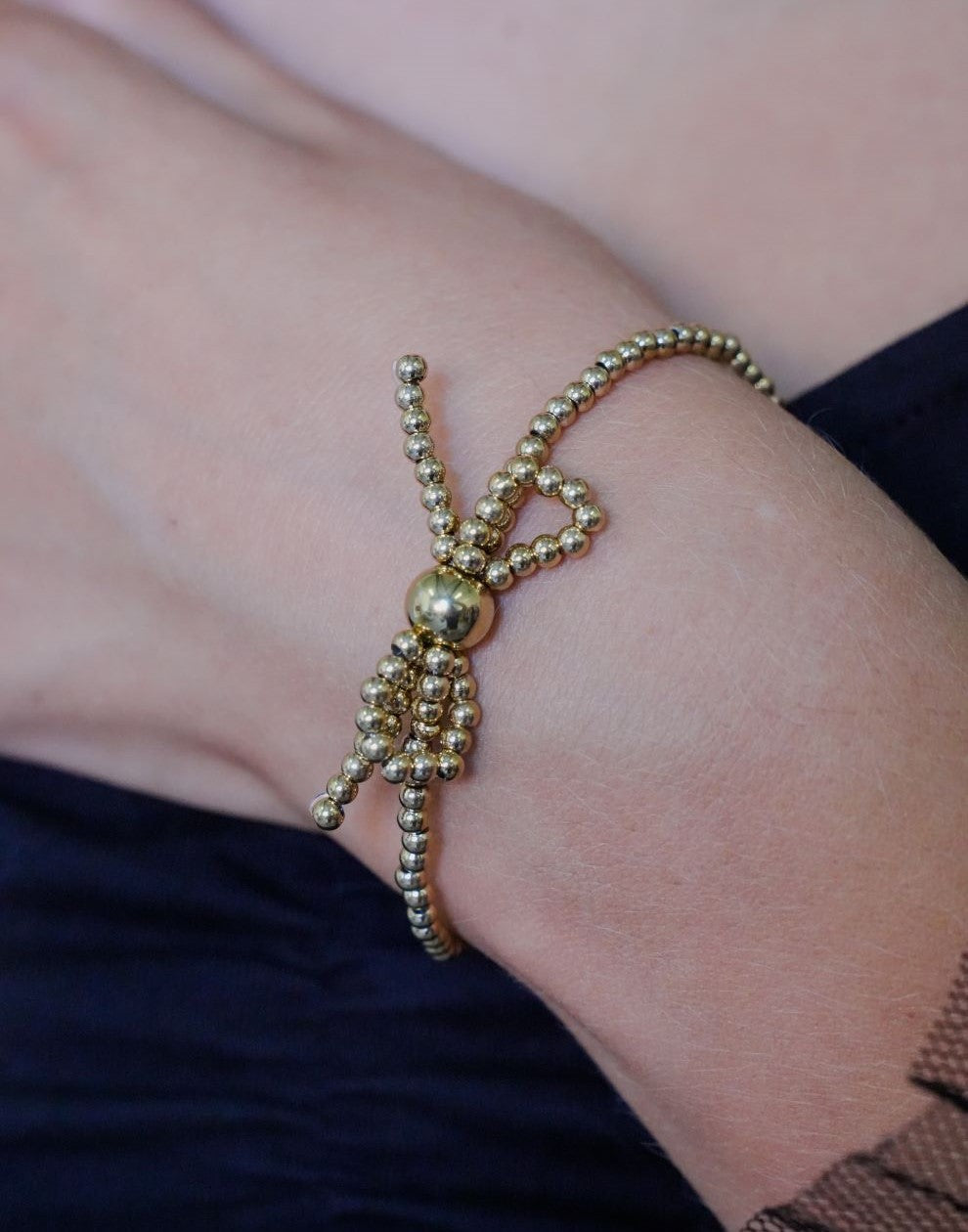 Stretch armband bolletjes strik goudkleurig