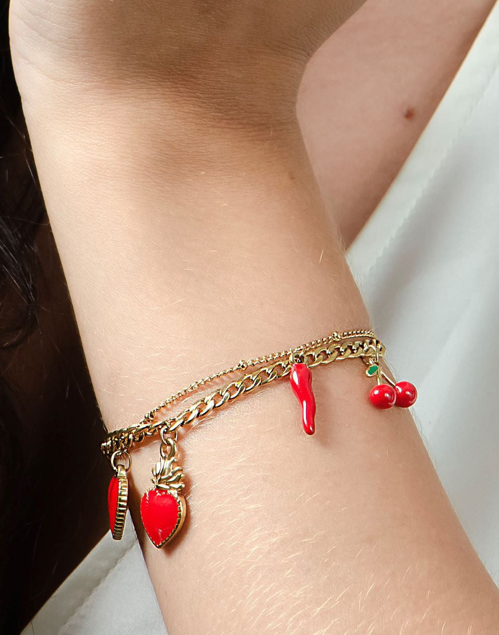 Schakelarmband rode bedels goudkleurig