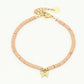 Armbandje roze met vlinder hanger in het goudkleurig